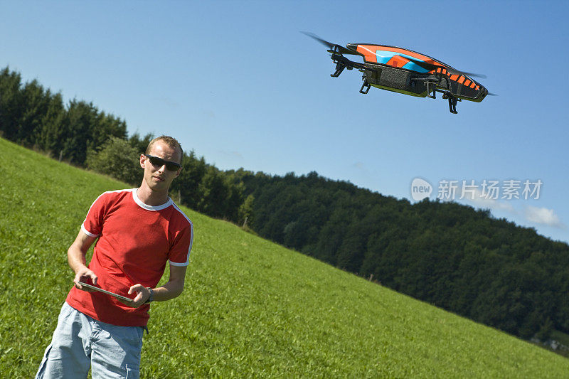 一个人站在开阔的田野里，开着无人机