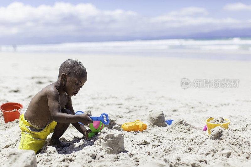 非洲男孩在海滩上建沙堡