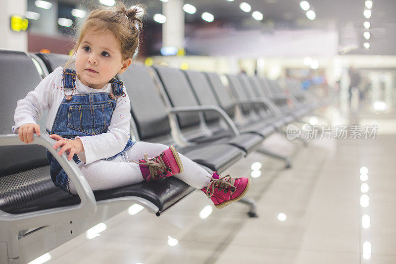 可爱的小女孩坐在机场等待