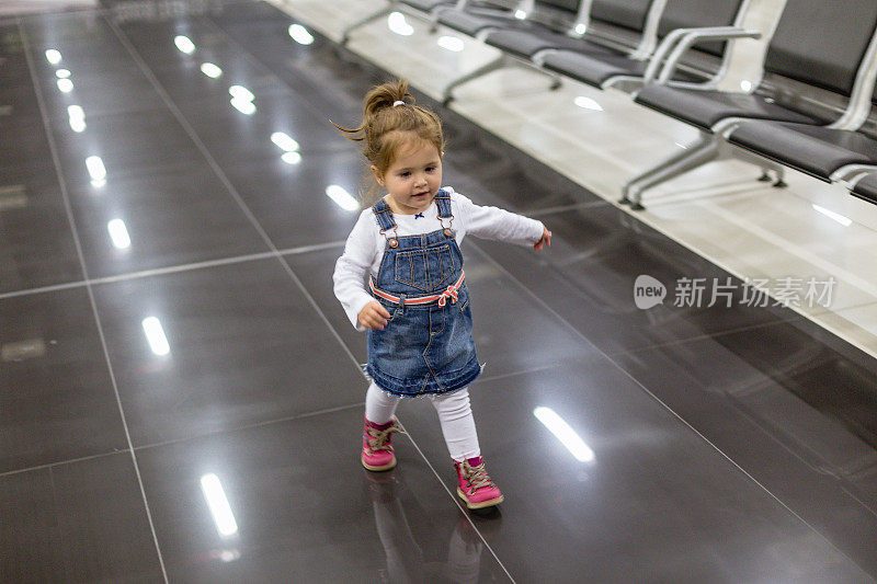 可爱的小女孩在机场等待航班时奔跑
