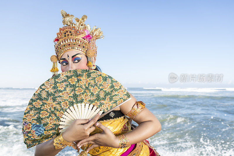 巴厘岛女舞者在传统服装与扇子在海滩上