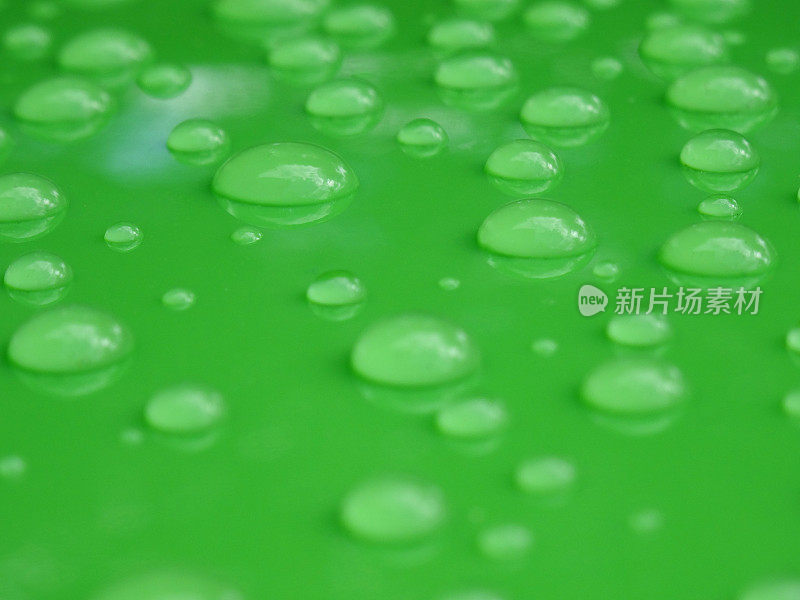 特写水滴图像，水滴墙纸背景上的绿色塑料