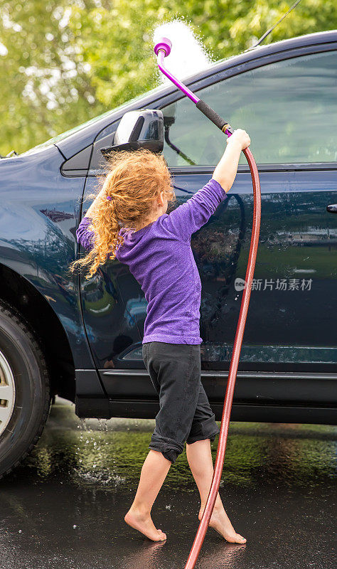 年轻女孩在车道上洗车
