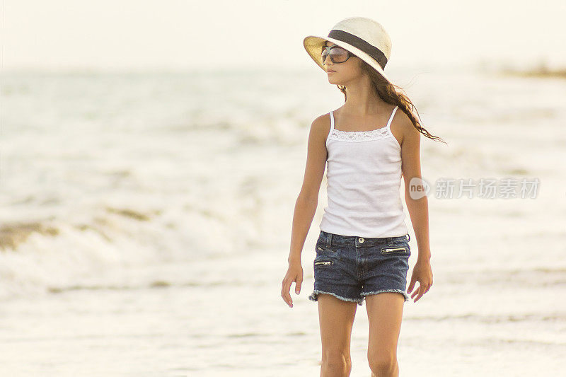 戴草帽的小女孩在海滩上散步