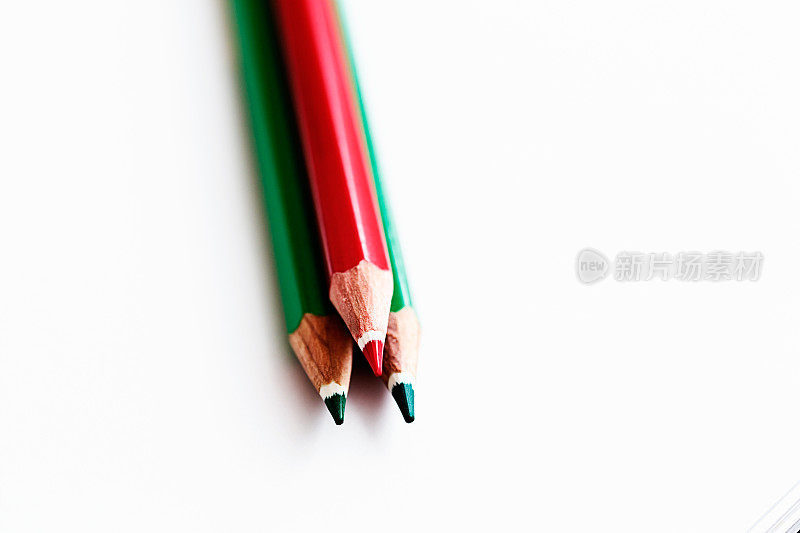 红色和两支绿色蜡笔指向白色