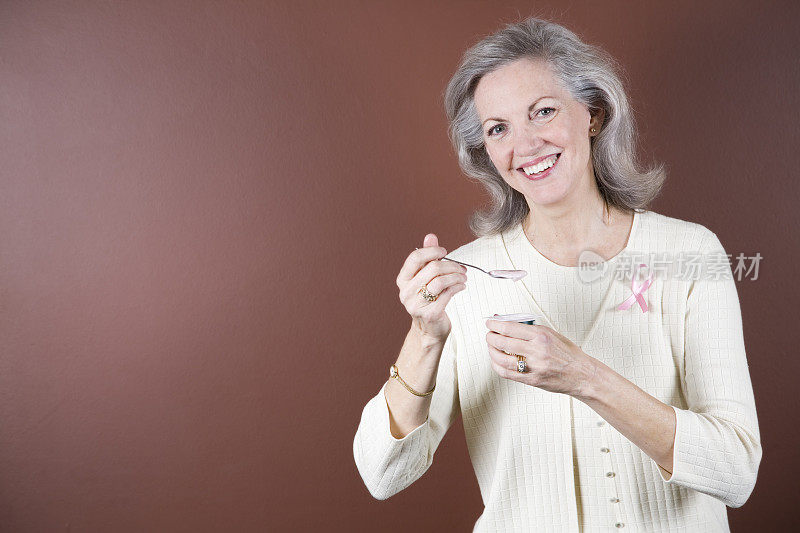 老年乳腺癌幸存者微笑着喝酸奶。