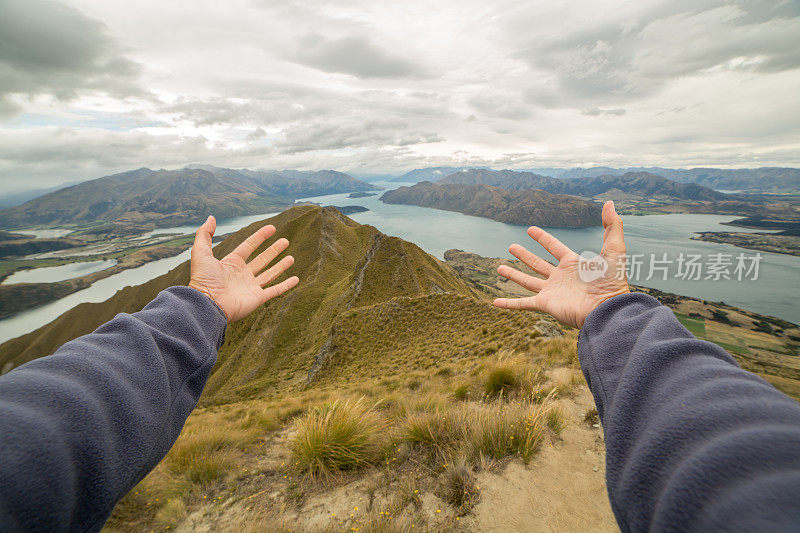 新西兰，女性的手臂伸向山地和湖泊景观