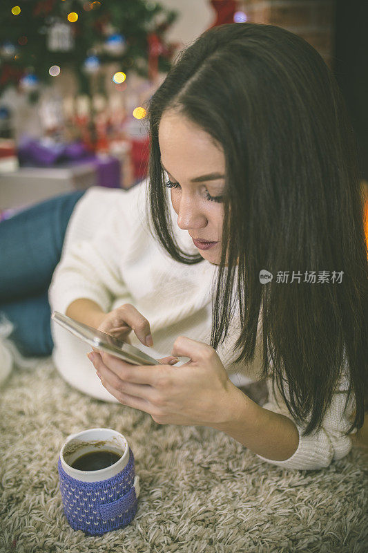 壁炉边拿着马克杯的女人。