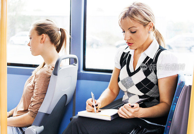 女商人乘公共汽车上下班时在笔记本上写字。