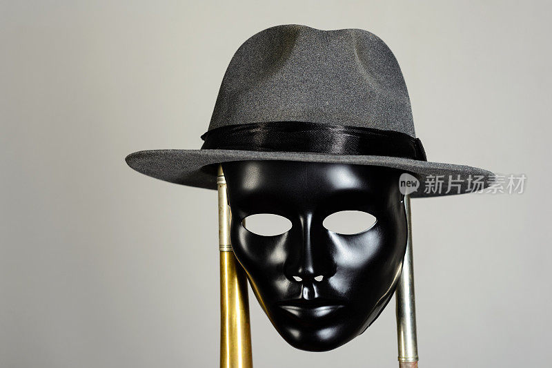 黑色剧场面具和帽子挂在黄铜管上