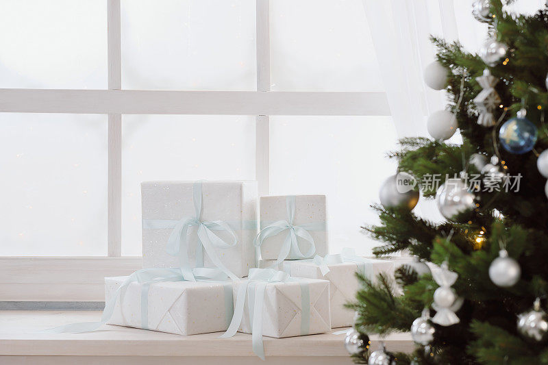 圣诞礼物装在白色的盒子里挂在圣诞树下的窗户上
