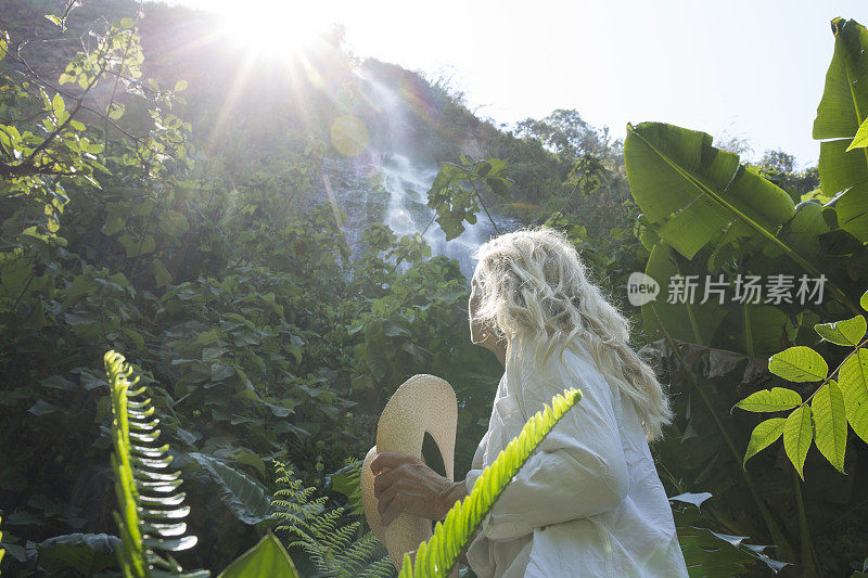 日出时，一名妇女仰望雨林中的瀑布