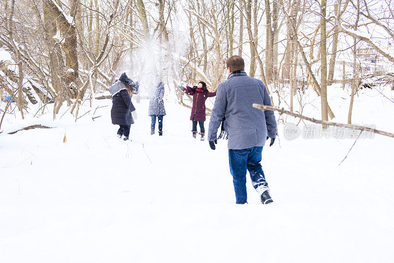 一群年轻人在冬天的一天在树林里打雪仗