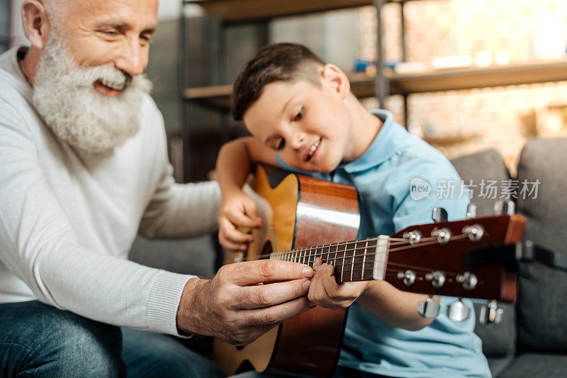 微笑的爷爷教孙子如何弹吉他