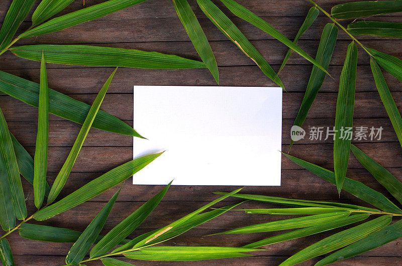 竹叶框架在乡村木制背景。竹叶花环上的空白纸。