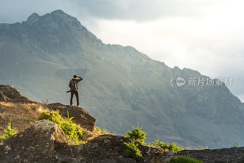 年轻的男摄影师在新西兰昆士敦看日落时的山景
