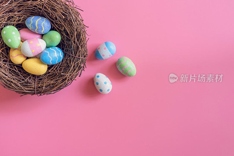 五彩缤纷的复活节彩蛋在巢上粉红色粉彩的背景与空间。