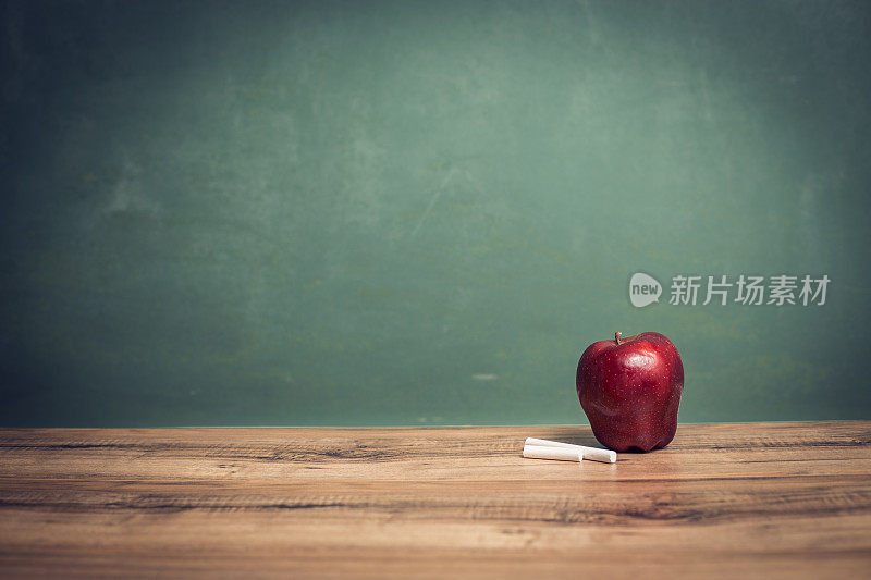 苹果，粉笔在木制课桌和黑板上。