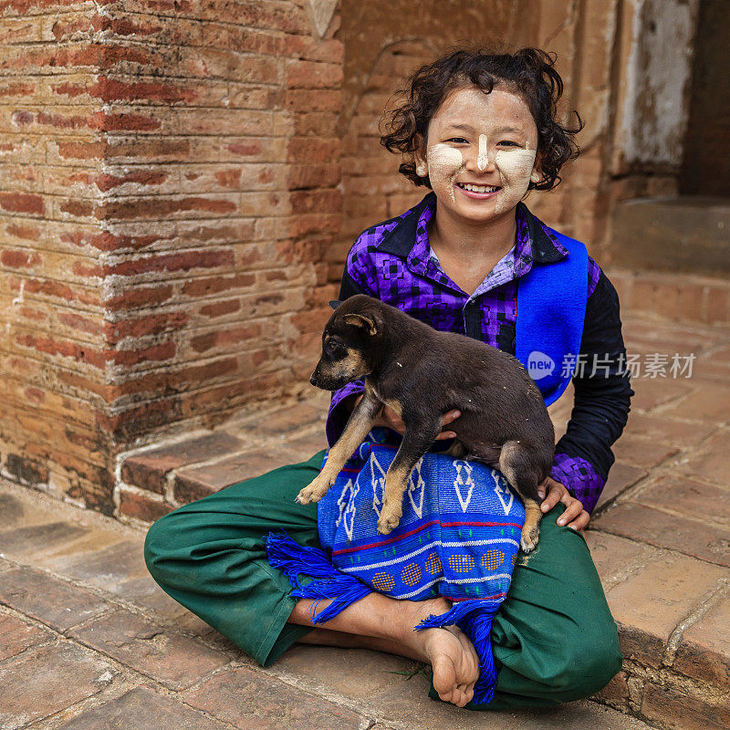缅甸老蒲甘的寺庙里，一个缅甸小女孩和一只狗坐在一起