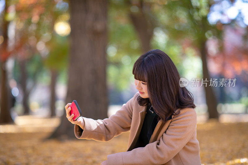 年轻女子在秋天的森林里自拍