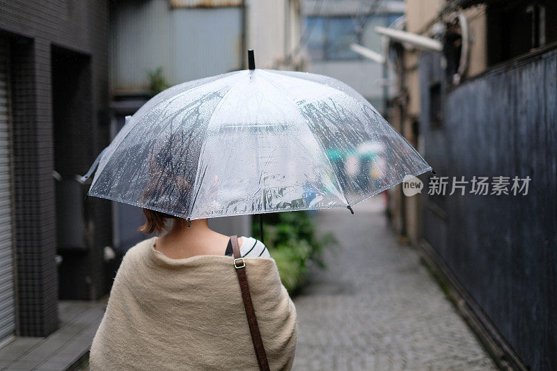 在一个雨天，在东京神乐坂传统老城的小巷里走着的女人的背影