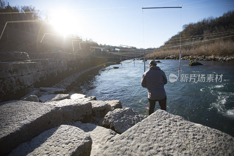 年轻的成年男子站在河岸上看皮划艇激流回旋赛道