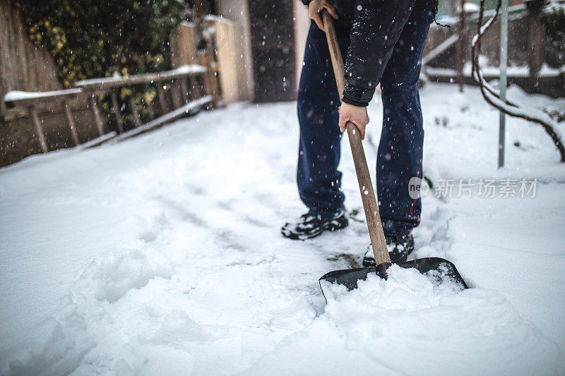 一位老人正在后院除雪