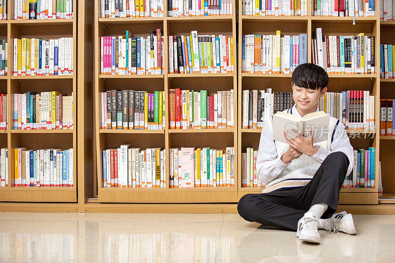 倚在书架上看书的学生