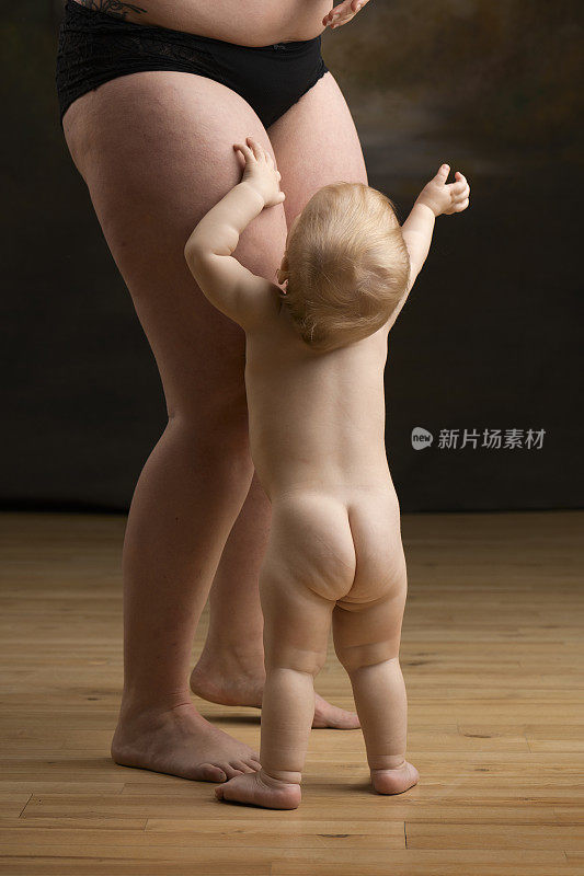 孩子站在他妈妈面前的地板上
