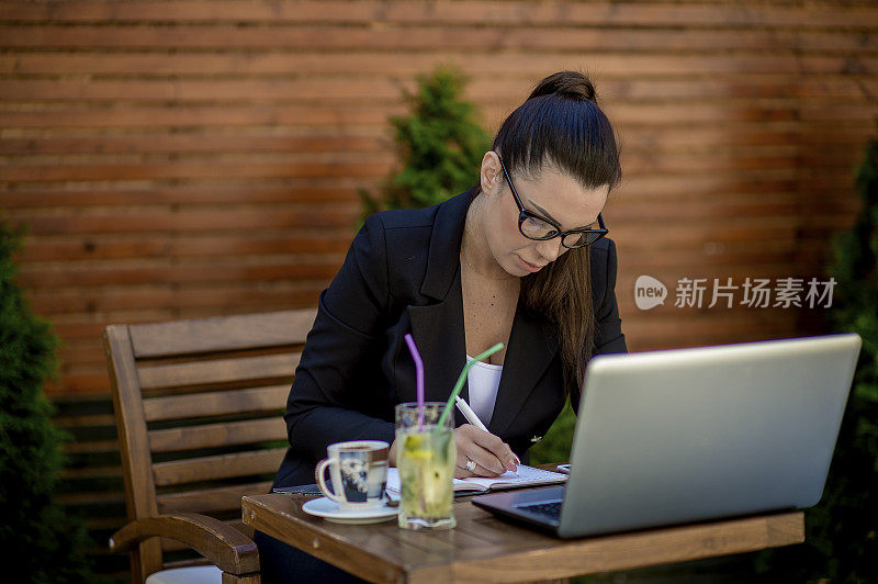 年轻的女商人在café用笔记本电脑工作