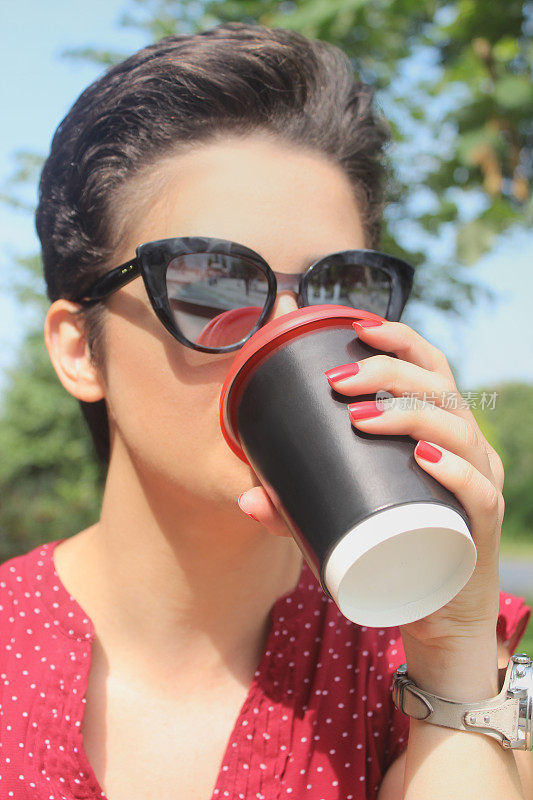 一个年轻女人用可重复使用的咖啡杯喝咖啡的肖像