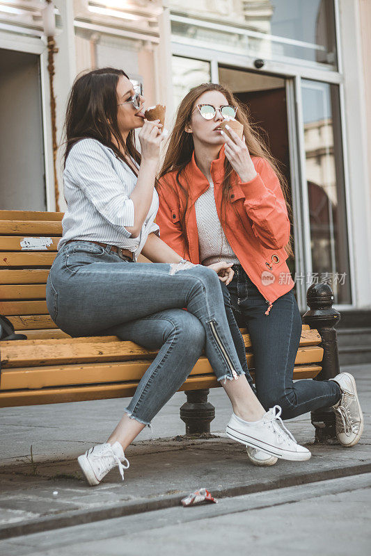 两个漂亮的女性朋友正在街上吃冰淇淋