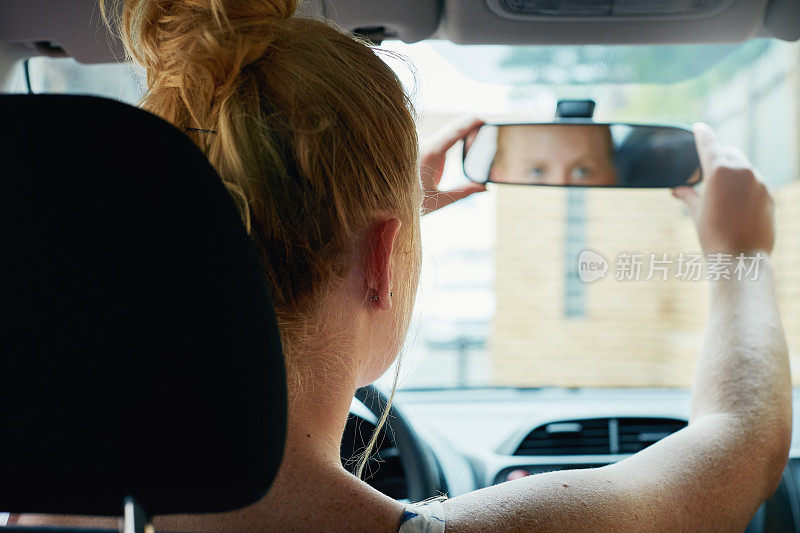 从车内看，年轻女子正在调整后视镜