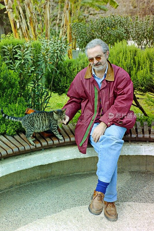 土耳其里维埃拉——一名游客在土耳其凯默附近的一个度假胜地的花园里抚摸着一只猫。