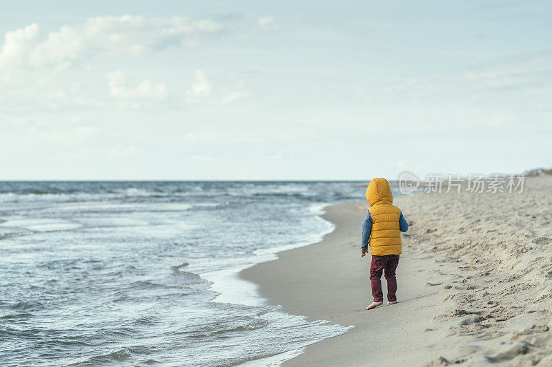 孩子在冬天或秋天在海边散步