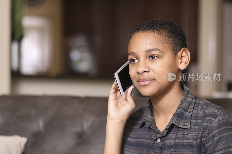 非洲裔少年在家里使用手机。