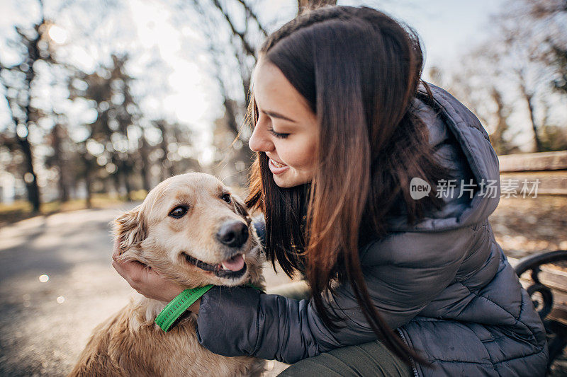 女孩坐在长椅上和寻回犬玩耍