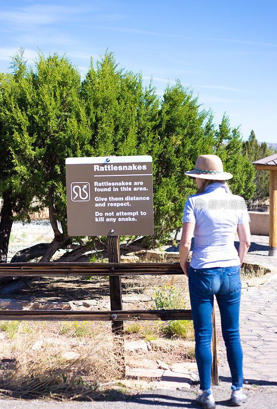 一名女子在自然公园阅读响尾蛇警告标志