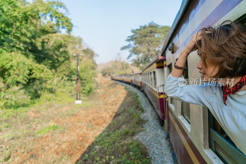 在泰国乘火车旅行的快乐女人从窗口望出去
