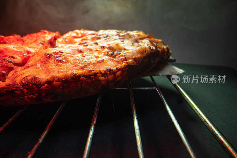 特写广角三分法微距拍摄美味的热气腾腾的深盘辣香肠披萨新鲜出炉的烤箱在冷却架下的加热灯与复制空间