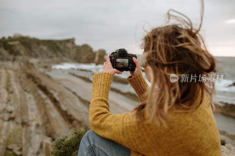 在海边用单反相机的年轻女子
