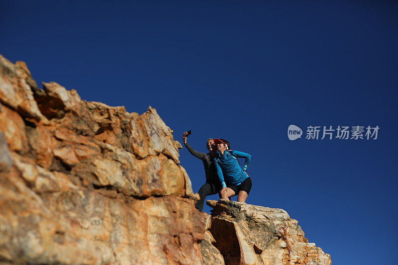 两个女性朋友站在一块岩石上自拍