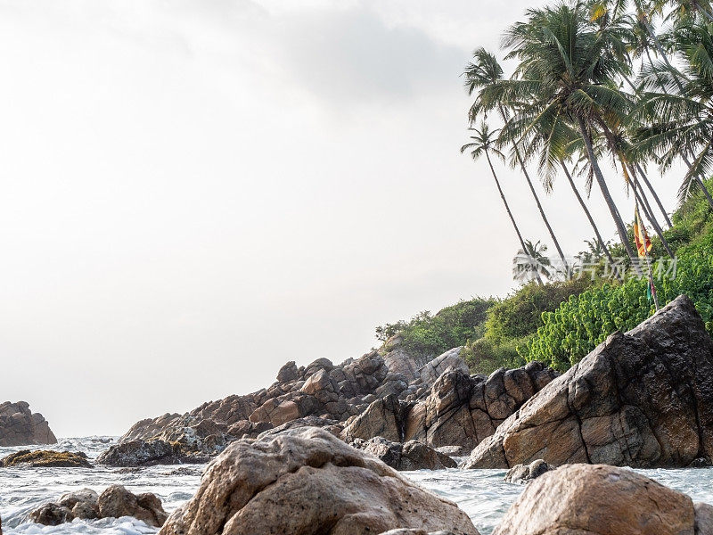 日落时斯里兰卡国旗在岩石上的海景，戏剧性的天空。没有人旅行