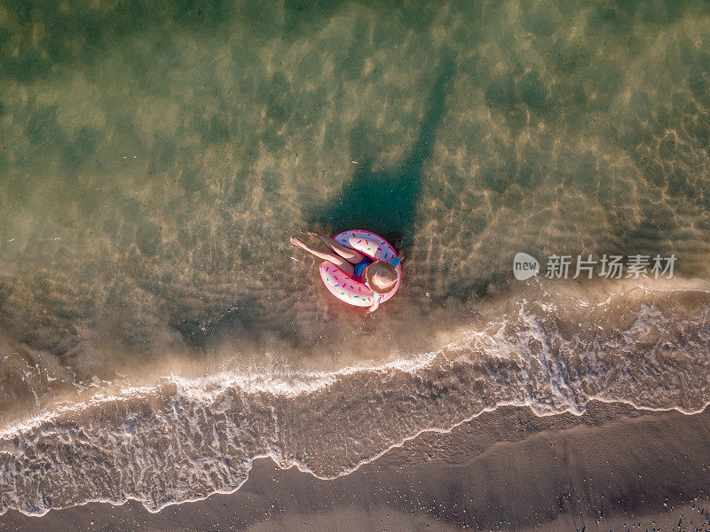 女人游泳和漂浮在海边的水与甜甜圈浮动鸟瞰图