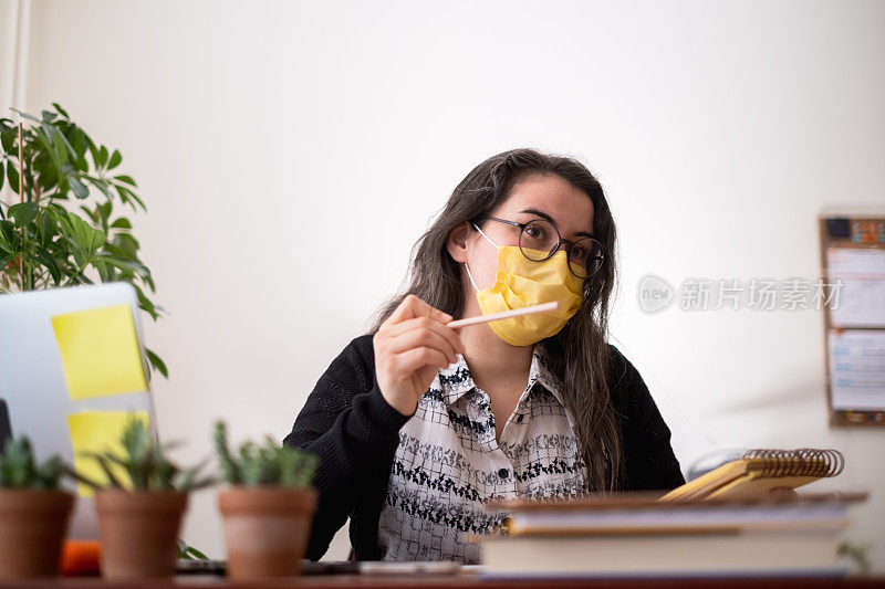 戴口罩在办公室工作的妇女