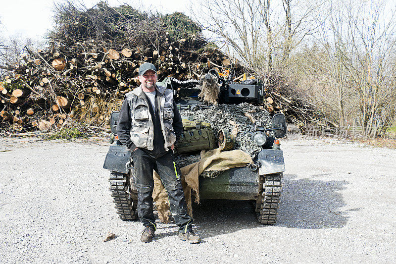 一个男人站在他的玩具坦克前