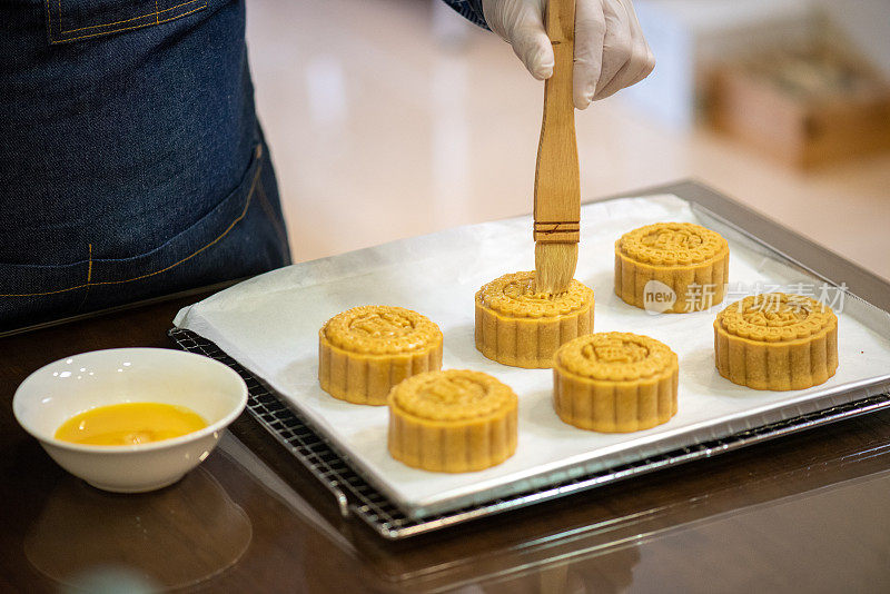 面包师在烤盘上用鸡蛋面团画自制月饼