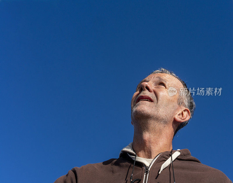 帆船上的一个人抬头看着帆，控制着它的位置