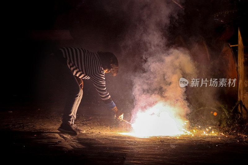 印度女子手持点燃的朋克(冒烟的棍子)，弯腰点燃喷泉烟花，这是印度传统的灯节，排灯节