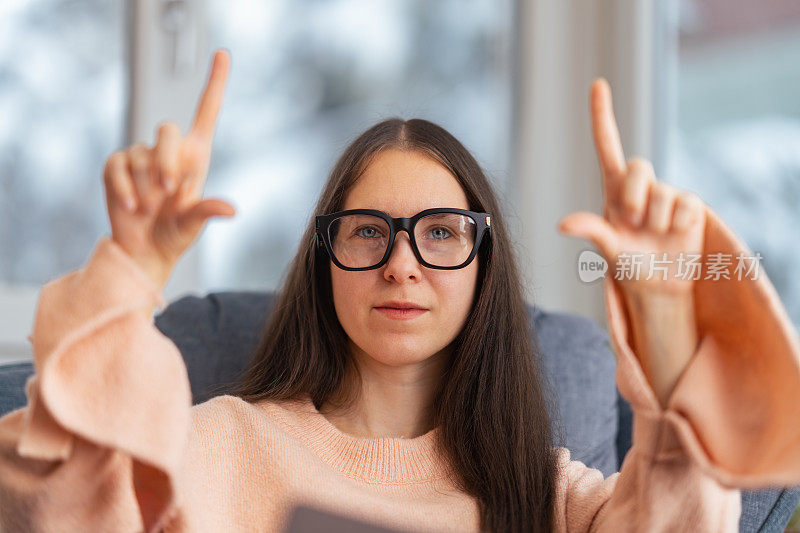 美丽的女商人坐在沙发上的肖像和使用智能眼镜。元境智能眼镜虚拟现实技术概念